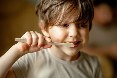 The boy brushes his teeth with a toothbrush made of ecological material