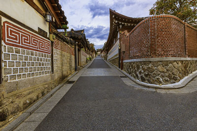 Empty road amidst buildings against sky