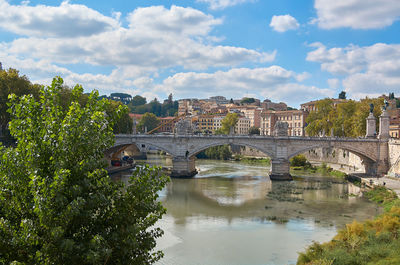 Bridge over river in city against sky