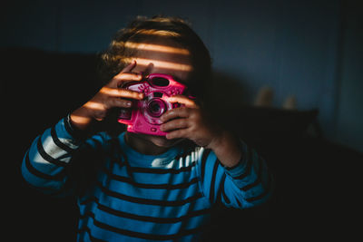 Young child pretending to take a photo with toy camera inside at home