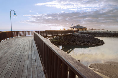 Pier over lake against sky during sunset