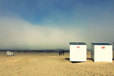 Hooded chairs on beach against sky