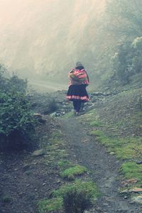 Rear view of woman walking on footpath in forest