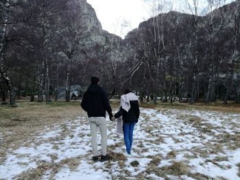 Rear view of friends walking on snow covered trees