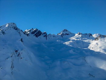 Scenic view of snowcapped mountains against clear blue sky