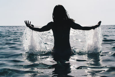 Silhouette woman standing by sea against sky