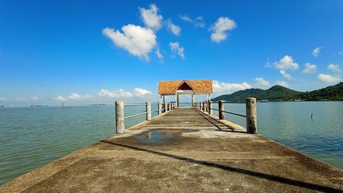 Pier over sea against blue sky