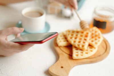 Midsection of person holding coffee cup on table