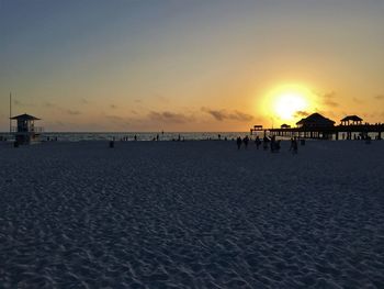 Silhouette people on beach against sky during sunset