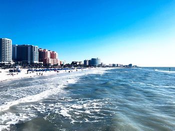 Scenic view of sea and buildings against clear blue sky