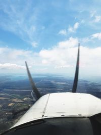 Close-up of airplane wing over landscape against sky