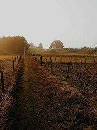 View of field separated by fence against clear sky