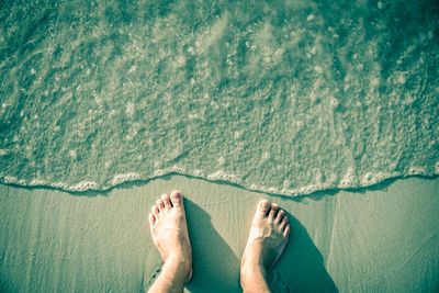 Low section of man standing on shore at beach