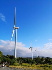 Low angle view of wind turbines on field against sky