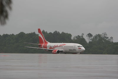 Side view of airplane on runway against sky