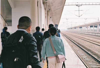 Rear view of people waiting at railroad station