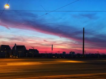 Street by buildings against sky at sunset