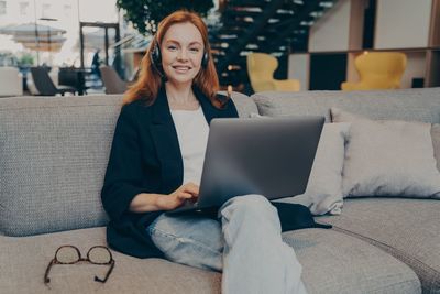 Portrait of young woman using laptop while sitting on bed at home
