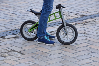 Low section of person with child's bicycle on road in city