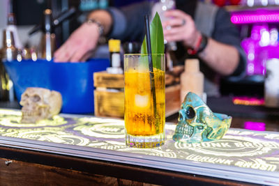 Midsection of man holding drink in glass on table