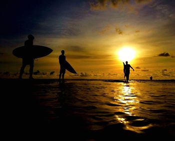 Silhouette people on beach against sky during sunset