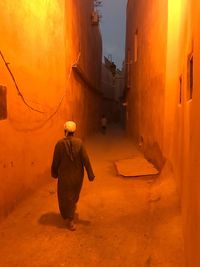 Rear view of man walking on street amidst buildings