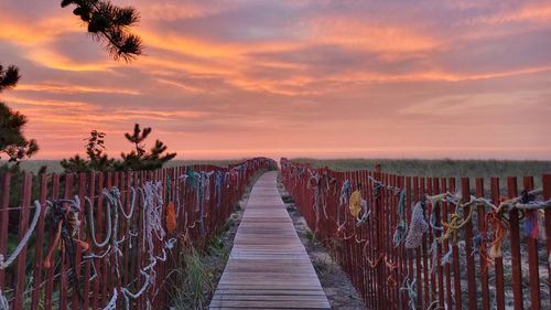 Rear view of woman walking on pier against sky during sunset