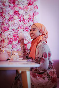 Happy girl looking away while standing against pink indoors