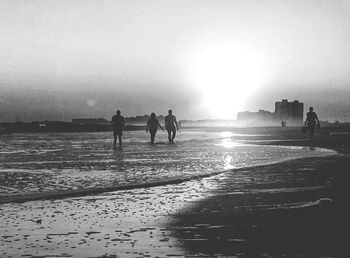 Silhouette people standing on beach against clear sky