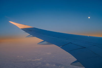 Airplane wing against sky during sunset