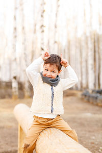 Portrait of cute boy sitting on the log outdoors