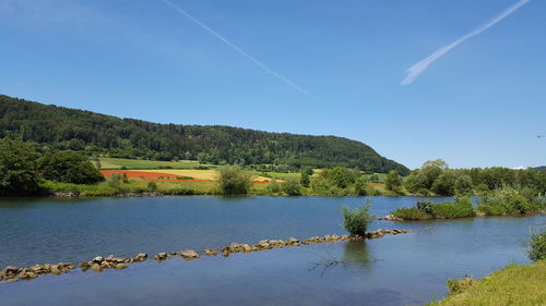 Scenic view of lake and mountains against blue sky