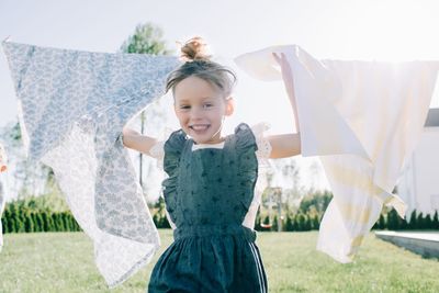 Portrait of a young girl playfully running through washing at home