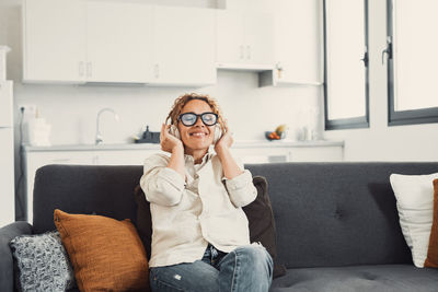 Young woman using mobile phone while sitting on sofa at home
