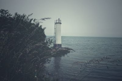 Lighthouse by sea against sky