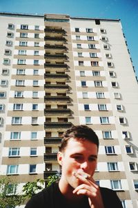 Low angle view of man smoking against building in city