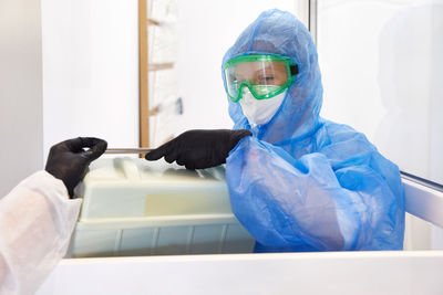 Scientist holding container while wearing protective suit