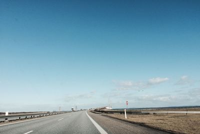 Empty road against clear blue sky