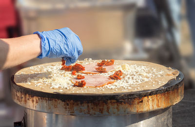 Close-up of person making large pancakes with cheese, ham and tomato