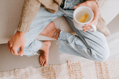 Midsection of man holding coffee cup on bed at home