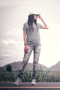 Full length of young woman standing against sky