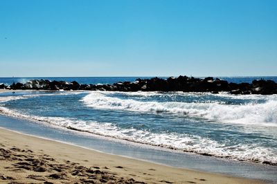 Scenic view of beach against clear blue sky