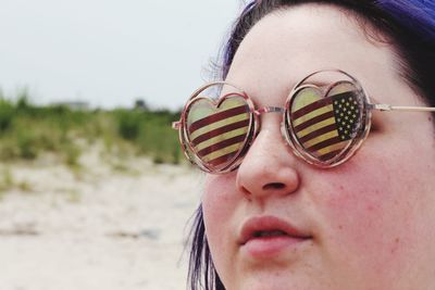 Close-up of young woman wearing sunglasses with flag pattern while standing outdoors