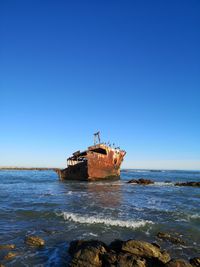 Ship in sea against clear blue sky