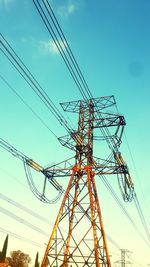 Low angle view of electricity pylon against blue sky