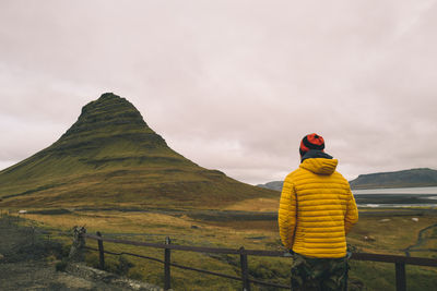 Rear view of woman standing on mountain against sky