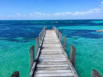 Pier over calm blue sea against sky