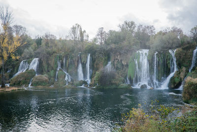 Scenic view of waterfall in forest against sky