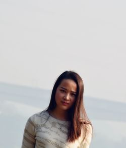 Portrait of young woman against sky