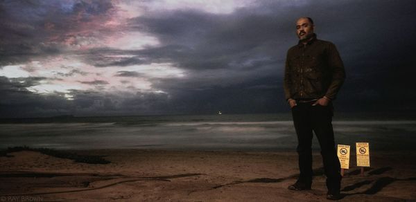 Man standing at beach against sky